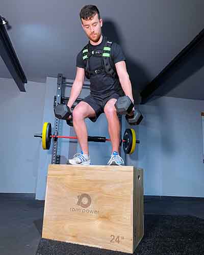man holding a pair of dumbbells standing on plyo jump box