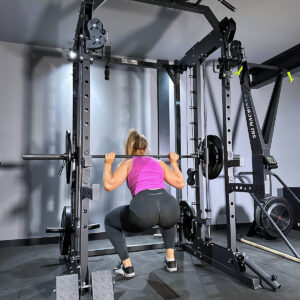 Woman performing squat under barbell on power rack
