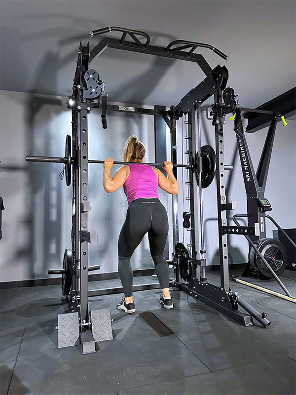 Woman performing squat under barbell on power rack
