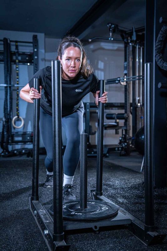 Woman using a weighted sled in hyrox